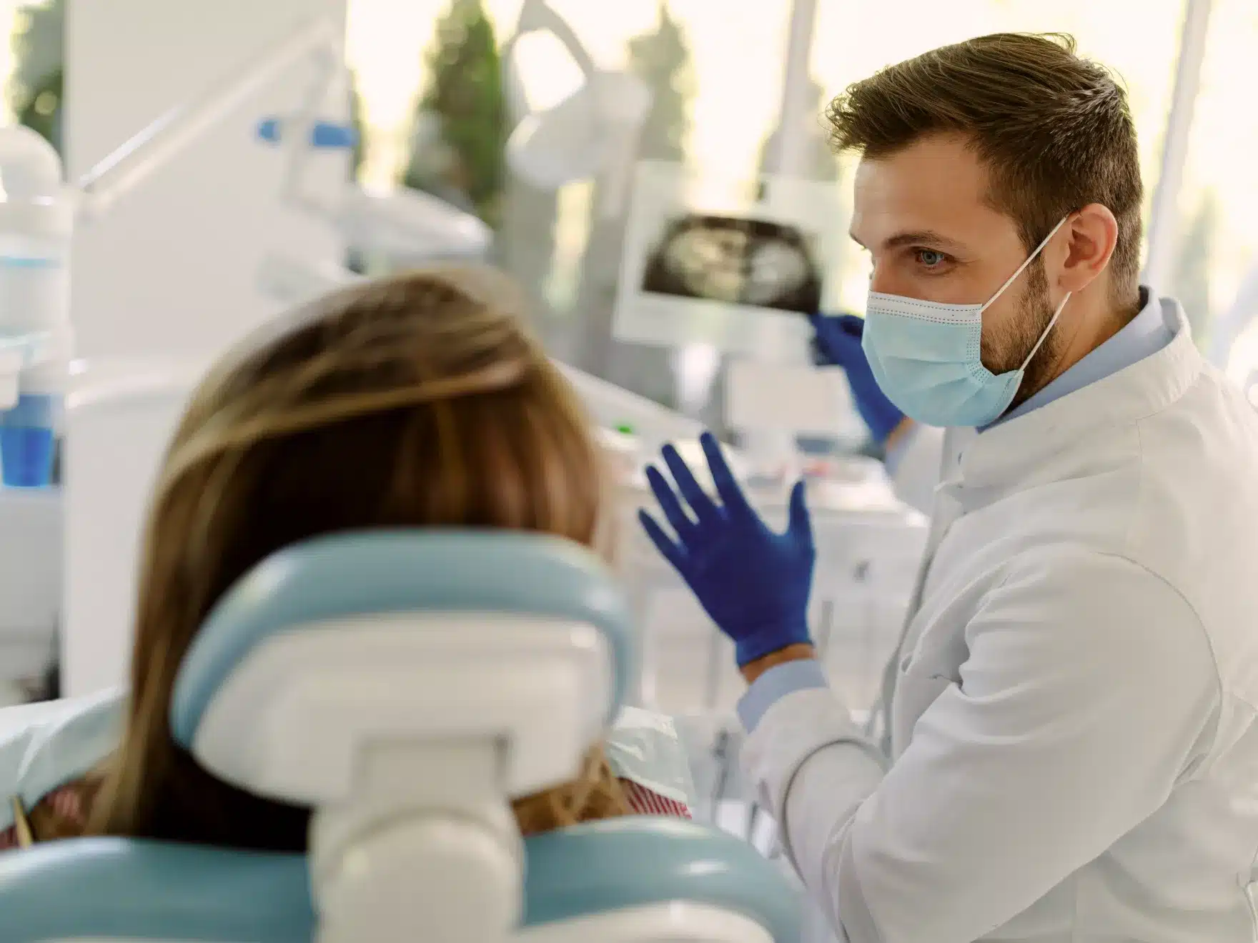 Male dentist reviewing digital X-rays with a female patient in the dental chair