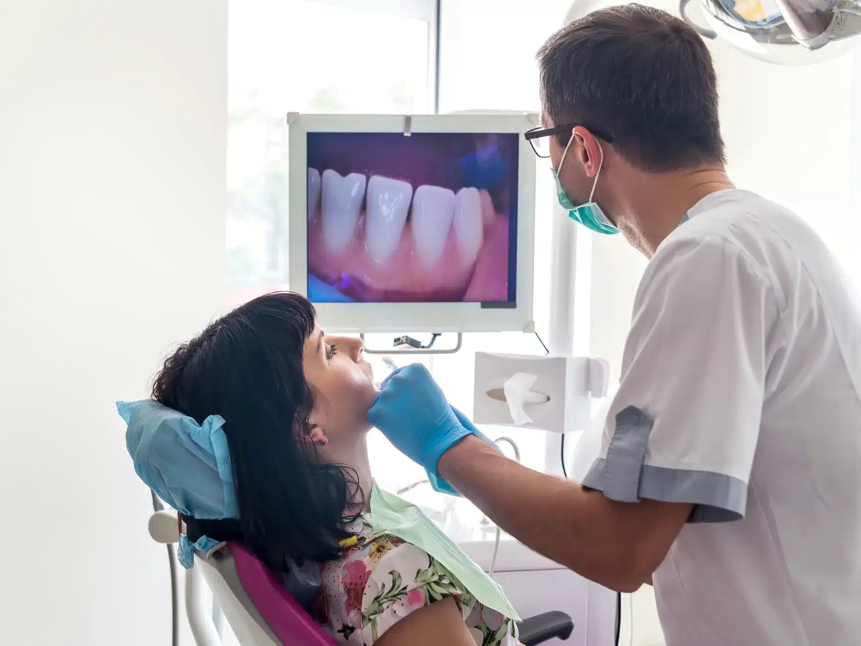 Male dentist examining a female patient with an intraoral camera